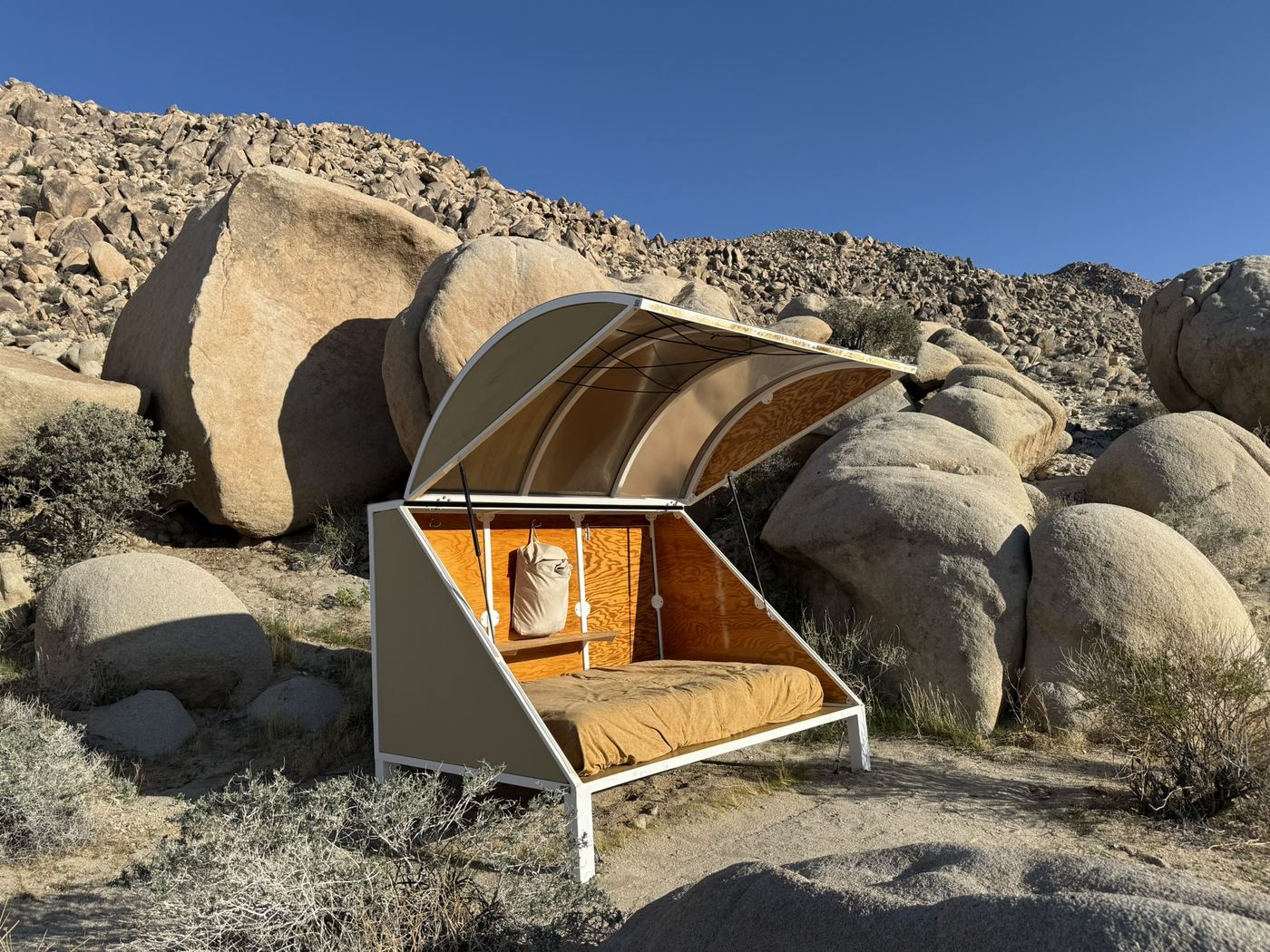 A small open-air sleeping shelter among desert boulders