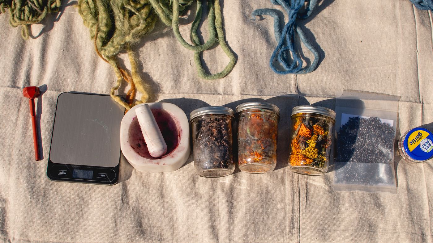 Dye table with scale, mortar, and jars of dried plants